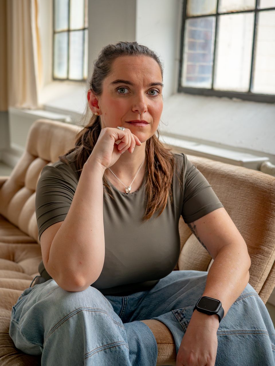 Miriam Göbel sitzt nachdenklich auf einem Sofa, die Hand am Kinn
