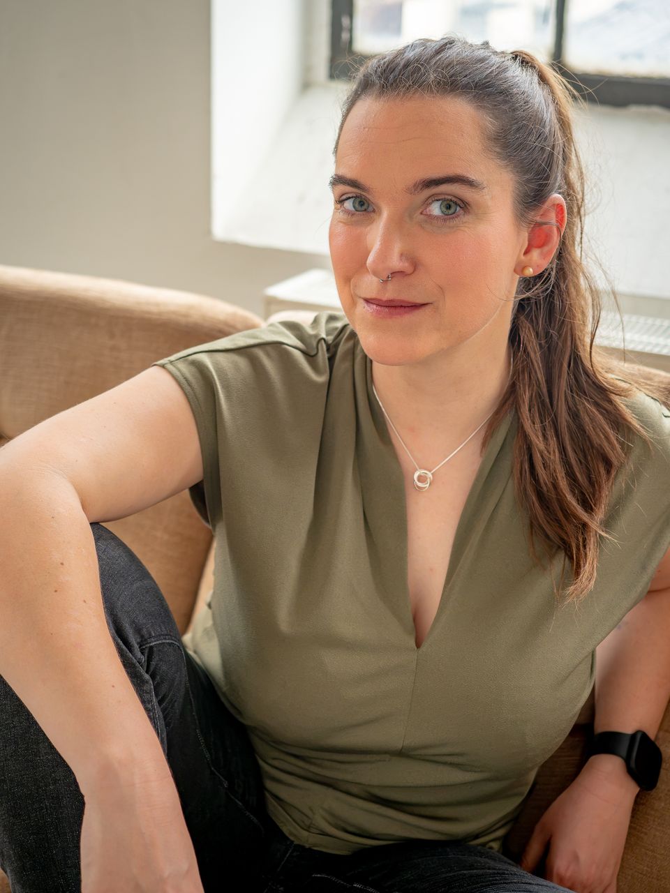 Miriam Göbel lehnt an einem Sofa vor einem Fabrikfenster